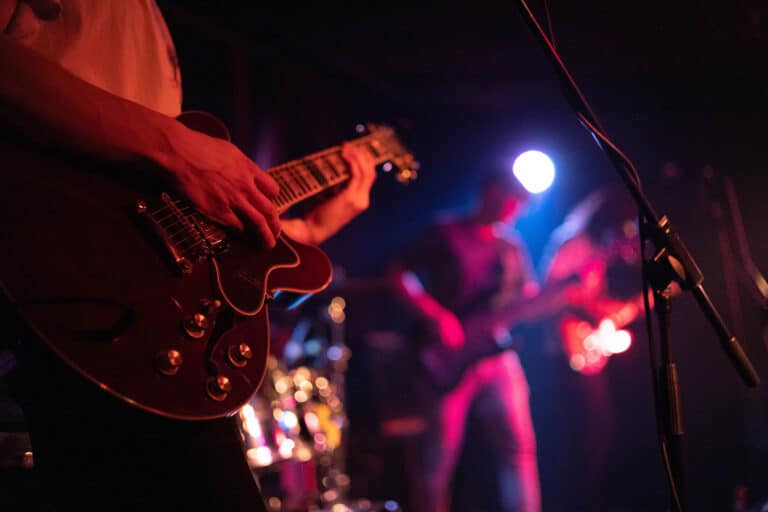 Musicians on stage strumming guitars during a live performance